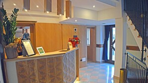 A reception area with a wooden counter, a potted plant, and a staircase.