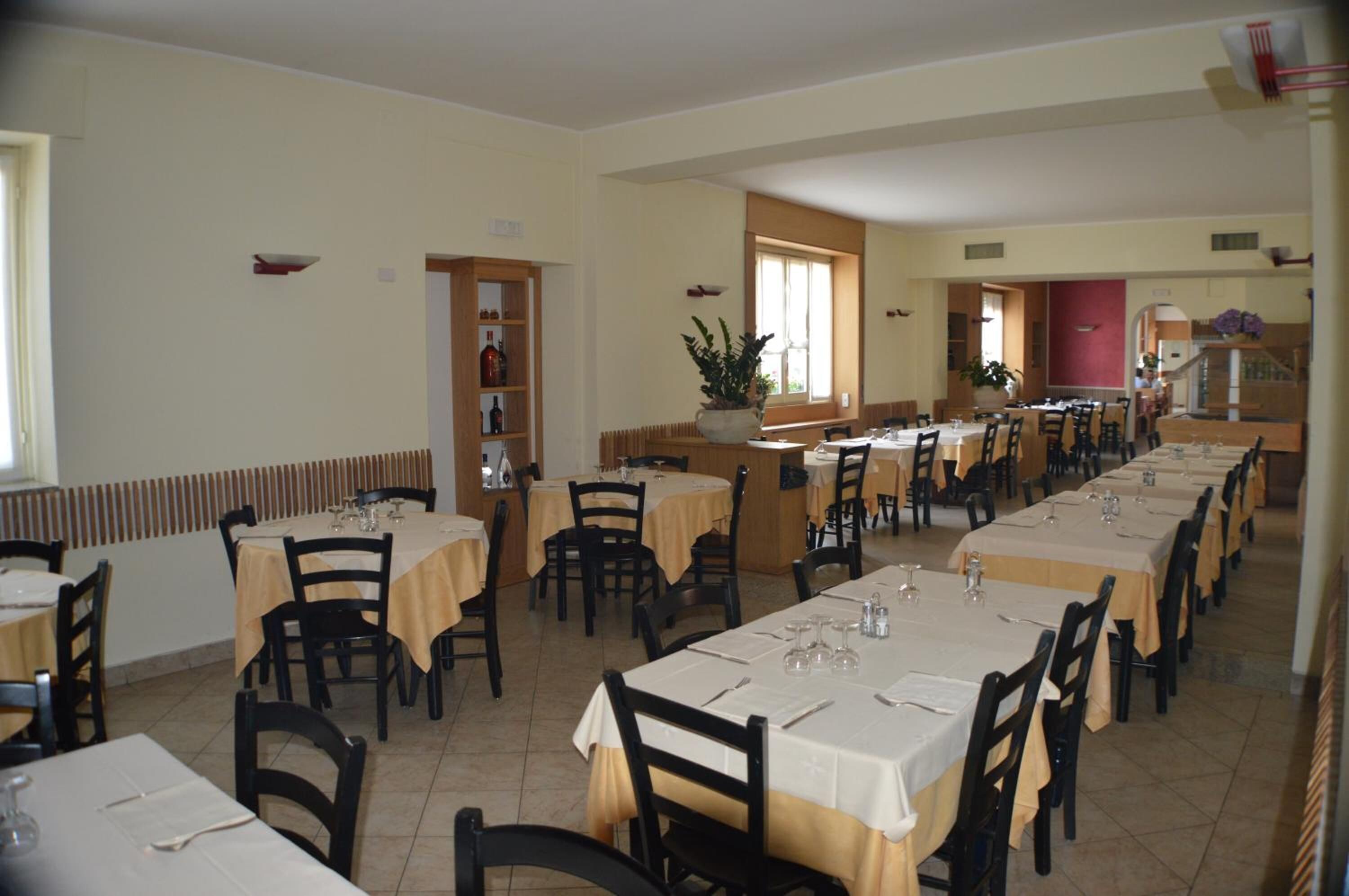Un espace repas comprenant plusieurs tables et chaises, une bibliothèque et une fenêtre laissant entrer la lumière naturelle.