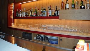 A bar area with shelves of liquor bottles and a row of glasses.