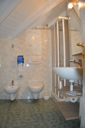 A bathroom with two toilets, a sink, and a shower.