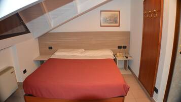 A bedroom with a bed, a nightstand, a bedside table, a wardrobe, and a painting on the wall.
