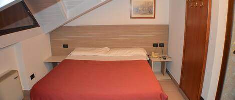 A bedroom with a bed, a nightstand, a bedside table, a wardrobe, and a painting on the wall.