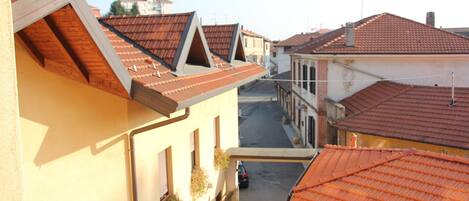 A narrow street with buildings featuring red-tiled roofs and a sloped design.