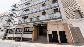 A multi-story hotel with a modern facade, featuring balconies, large windows, and a prominent entrance with a sign.