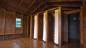Interior de una cabaña de madera con suelo de madera, un banco y una ventana con vistas.