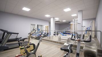 Un gimnasio con cintas de correr, bicicletas estáticas y máquinas de pesas.