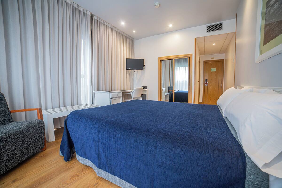 Een hotelkamer met een groot bed, een bureau, een stoel en een televisie.