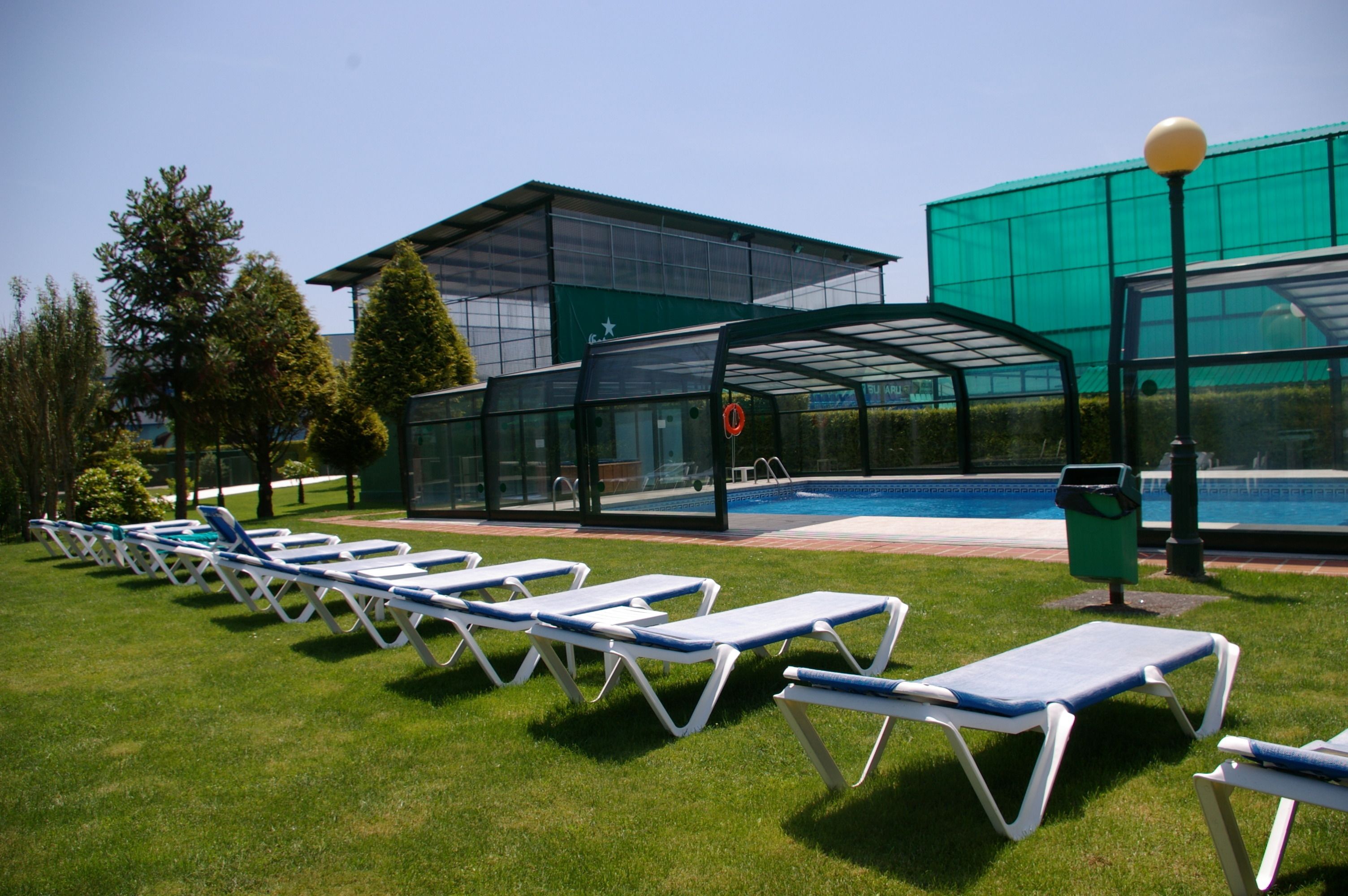A poolside area with lounge chairs, a covered seating area, and a building with a green roof.