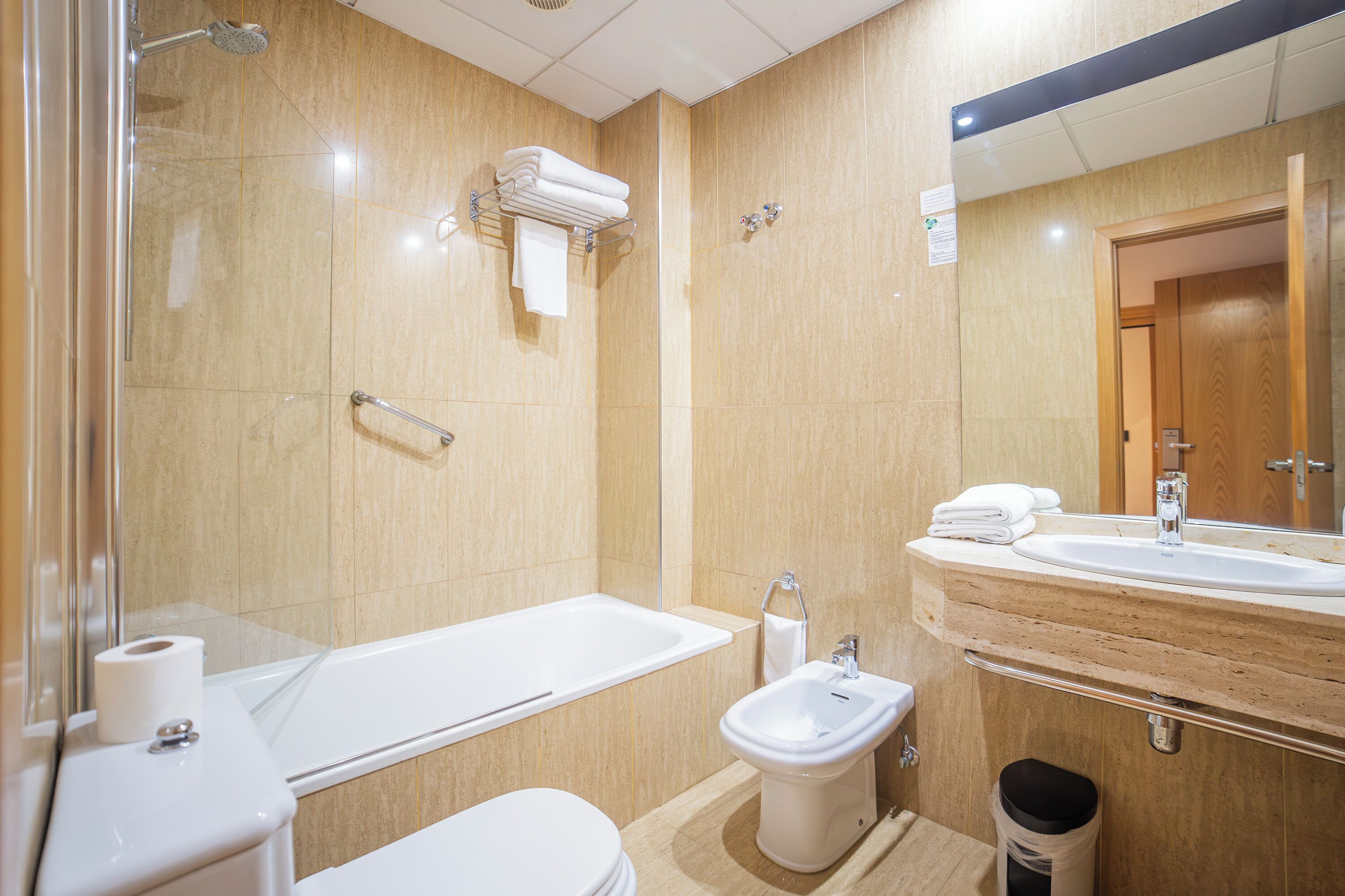 A modern bathroom with a bathtub, toilet, bidet, and sink.