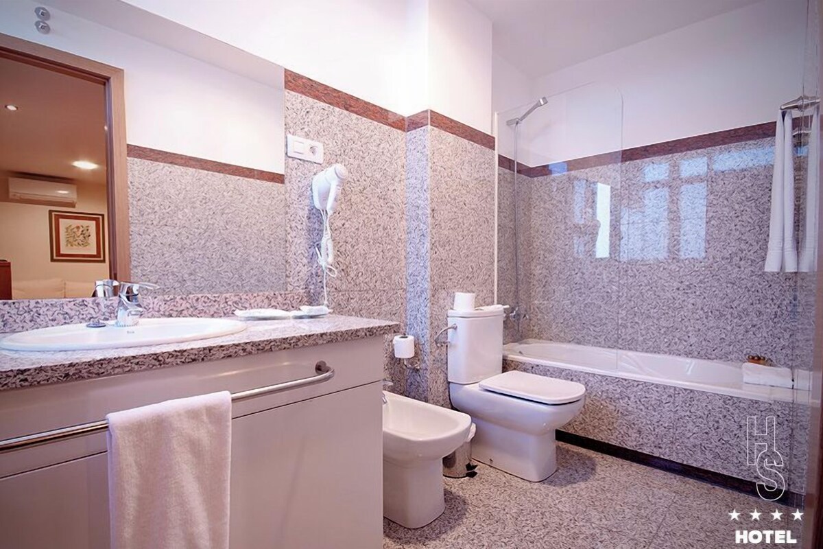 A modern bathroom with a sink, toilet, bidet, and shower.