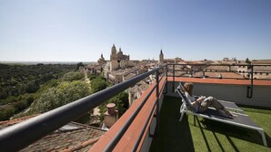 Un balcón con vistas a un casco histórico, que incluye una iglesia destacada y una torre del reloj.
