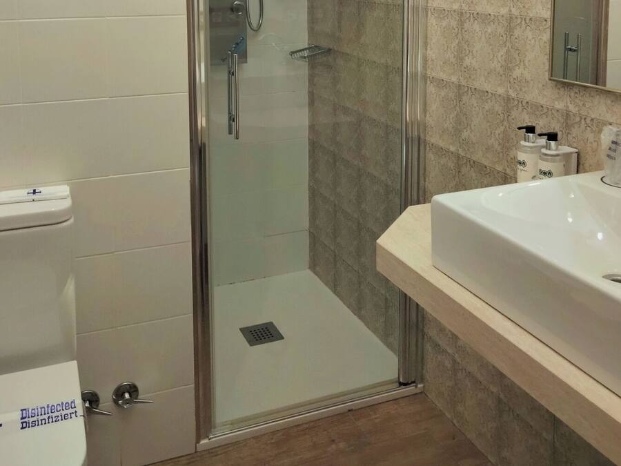 Une salle de bain moderne avec une douche à parois de verre, un lavabo blanc et un miroir.