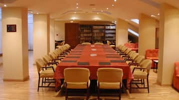 A conference room with a long table, chairs, and bookshelves.