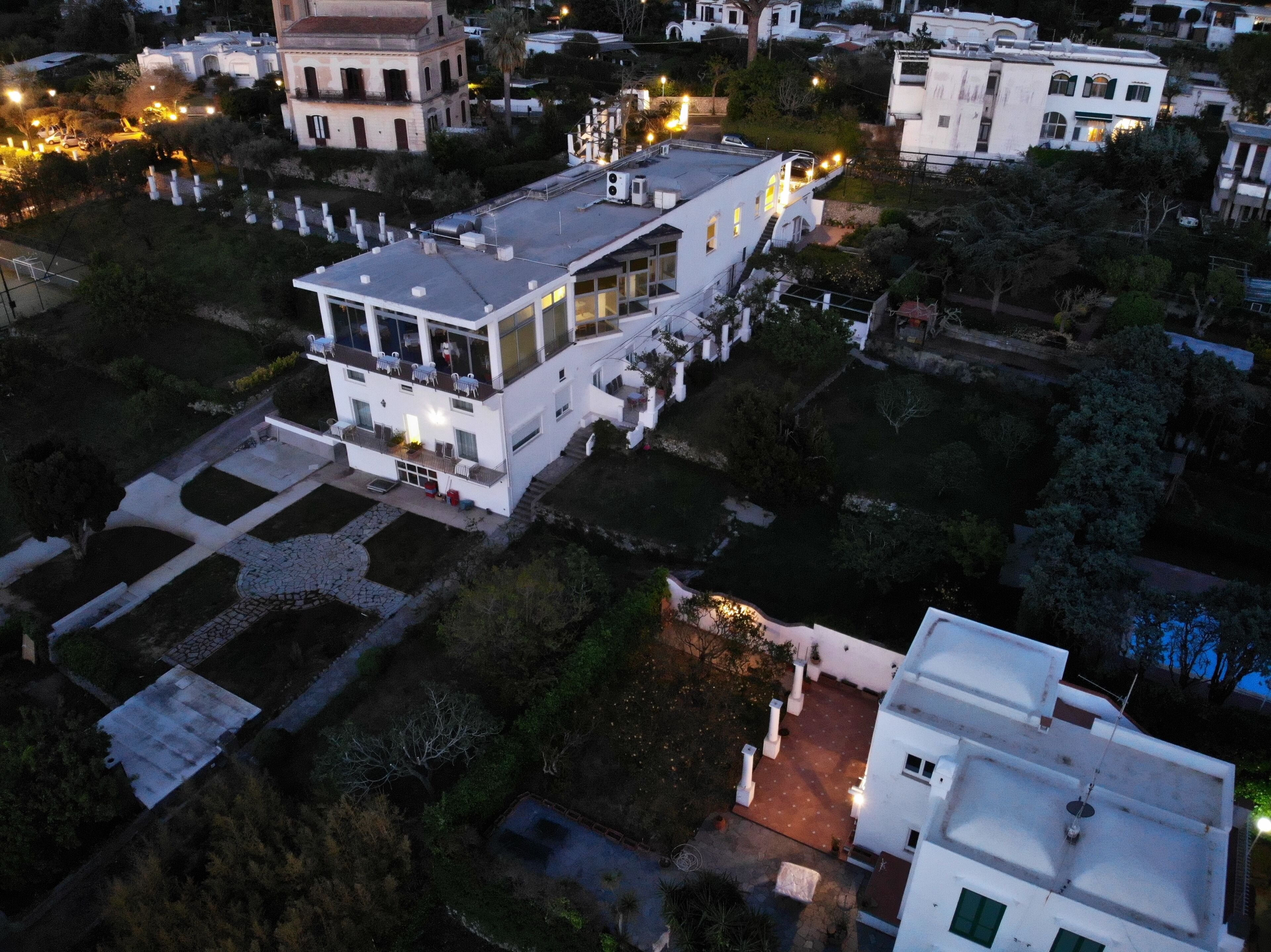 An aerial view of a modern building with a flat roof, large windows, and a spacious courtyard with a fountain.