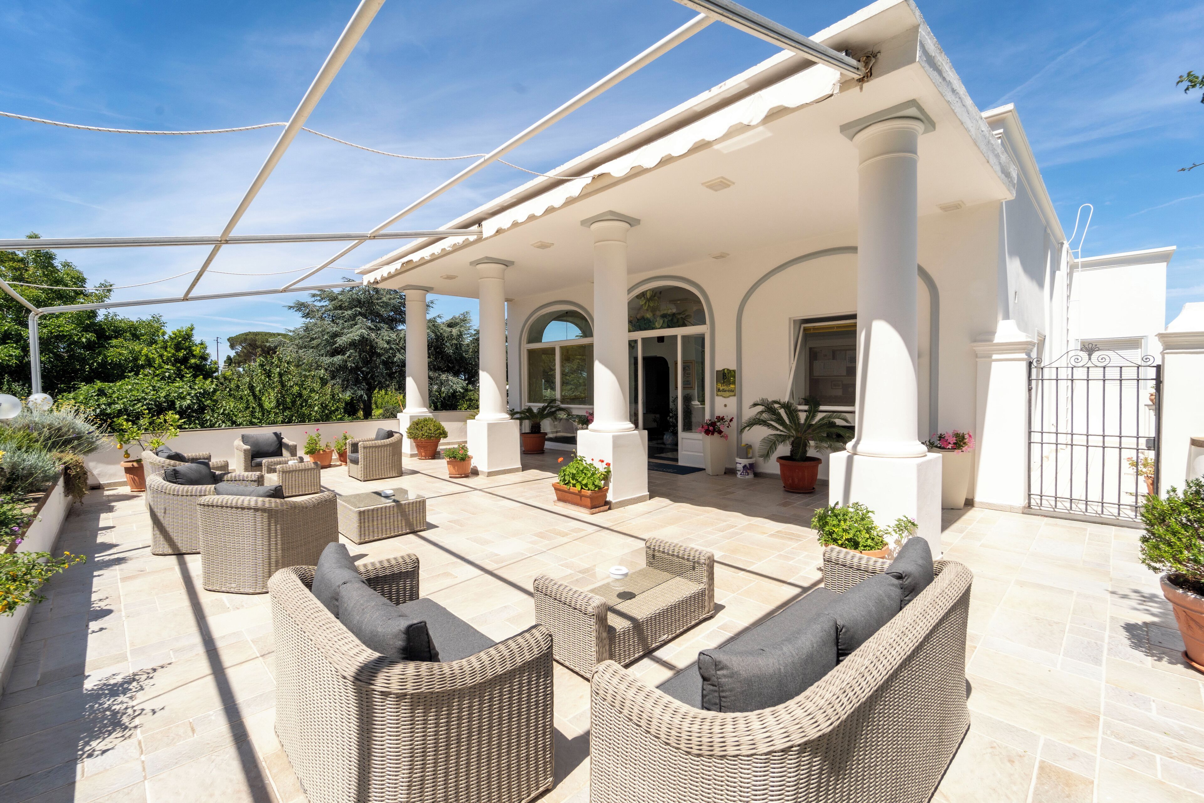 A covered outdoor patio with wicker furniture and potted plants.