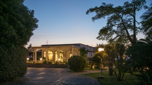 A building with a covered entrance, a stone pathway leading to it, and surrounding greenery. - Hotel Bellavista (Anacapri)