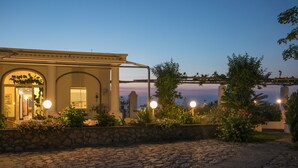 A building with a stone facade, arched windows, and a stone wall with plants. - Hotel Bellavista (Anacapri)