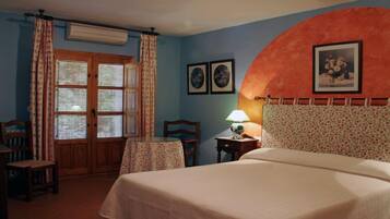 A bedroom with a bed, a desk, a chair, a table, and a window with curtains.
