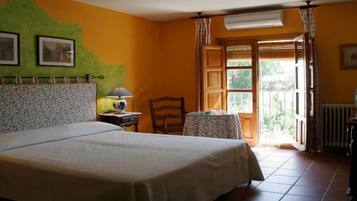 Un dormitorio con cama, una silla, una mesa y una ventana con cortinas.