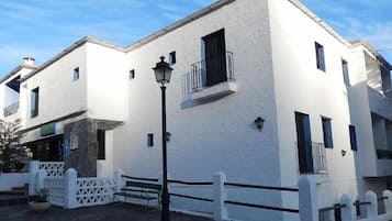 Un edificio bianco con un balcone, un lampione e un recinto in legno bianco.