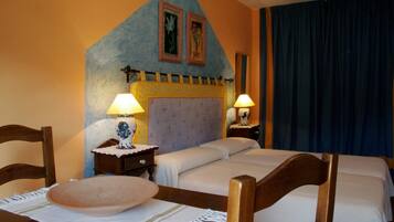 Habitación de hotel con una cama, dos mesitas de noche, una silla de madera, un muro decorativo y un ventanal con cortinas.