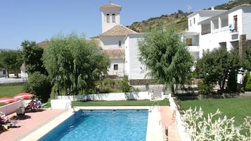 Una piscina al aire libre de temporada, sombrillas, tumbonas