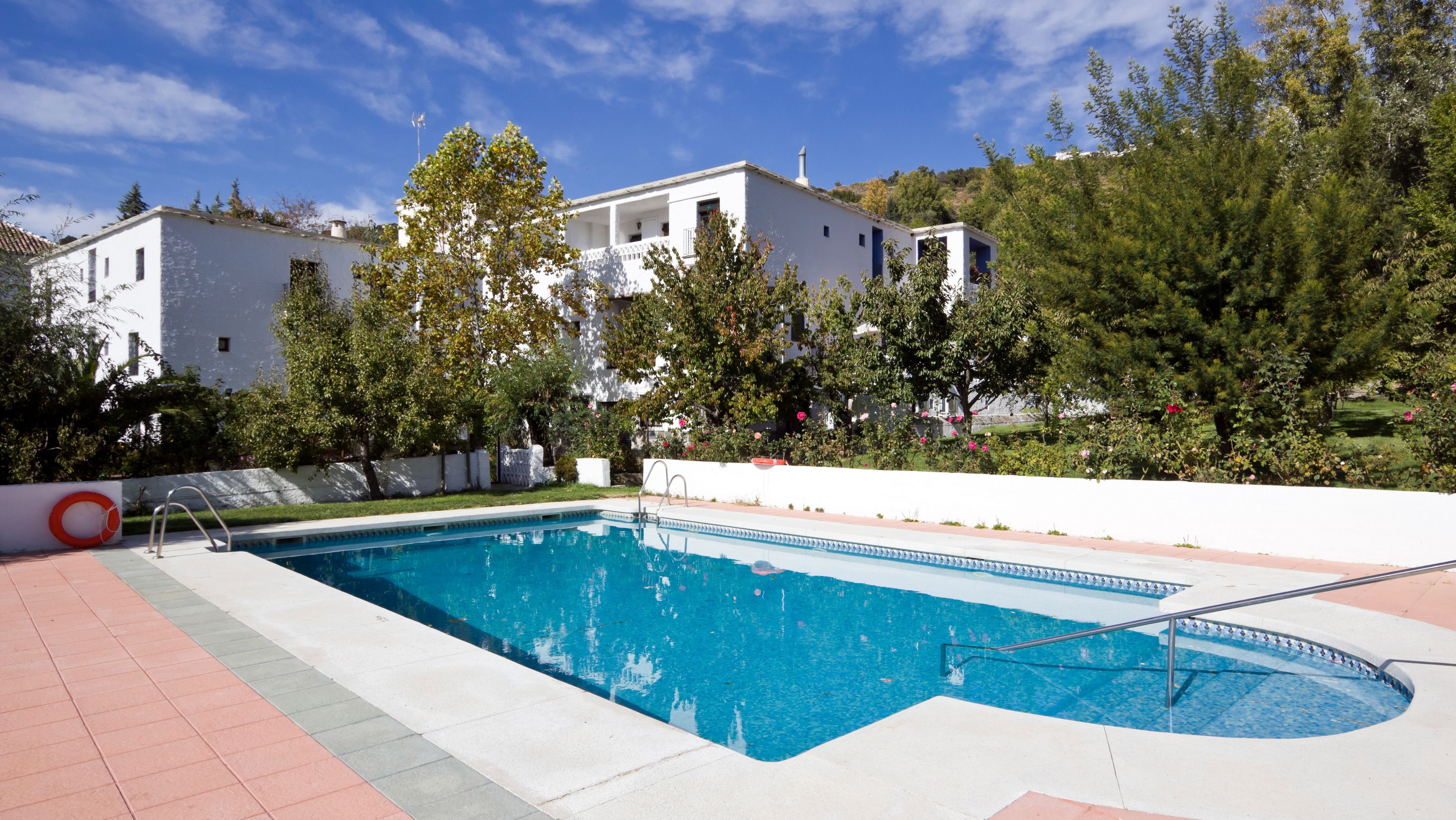 Una piscina al aire libre de temporada, sombrillas
