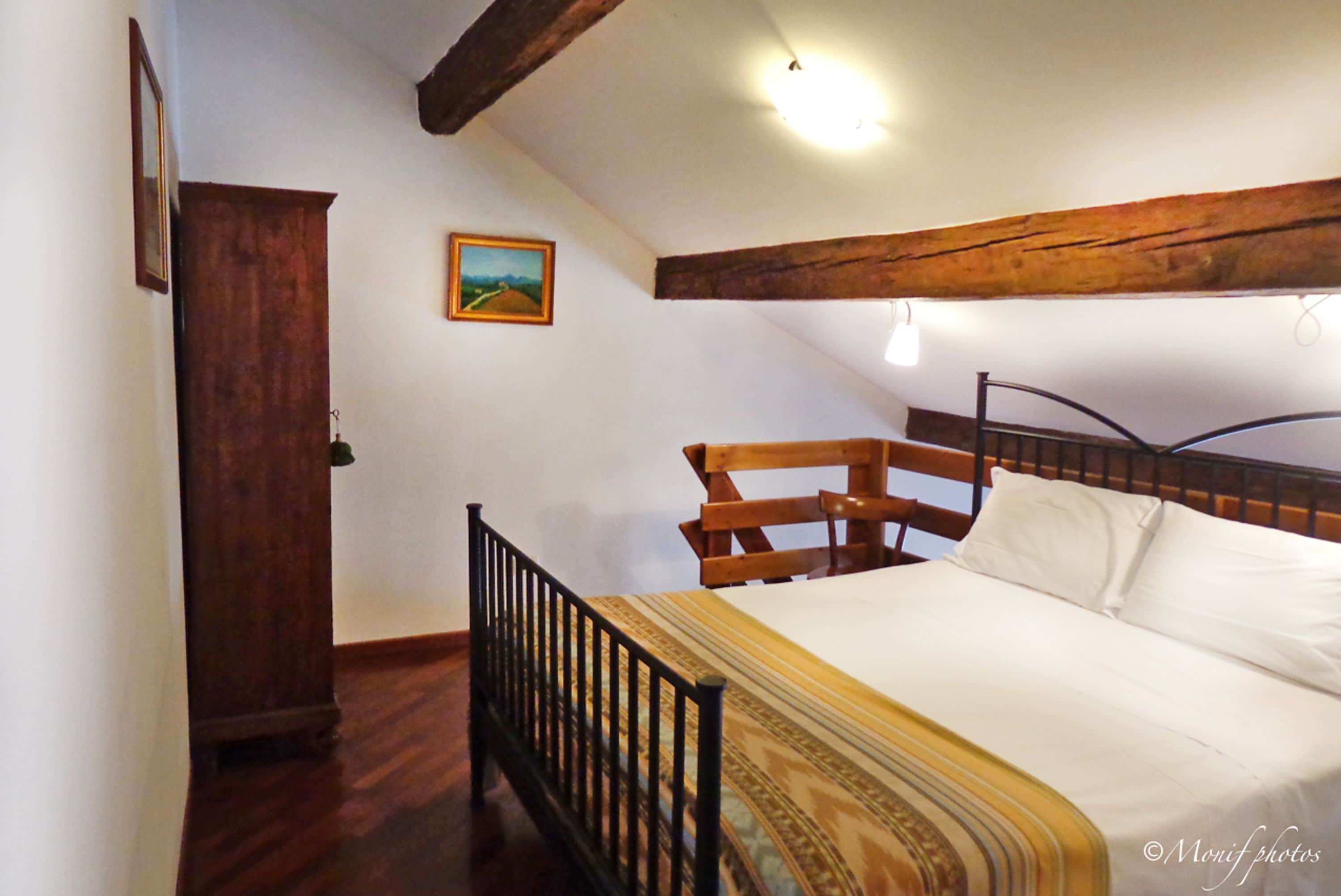 Ein Schlafzimmer mit einem hölzernen Bettgestell, einem Kopfteil, einem Schrank aus Holz und einem Bild an der Wand.