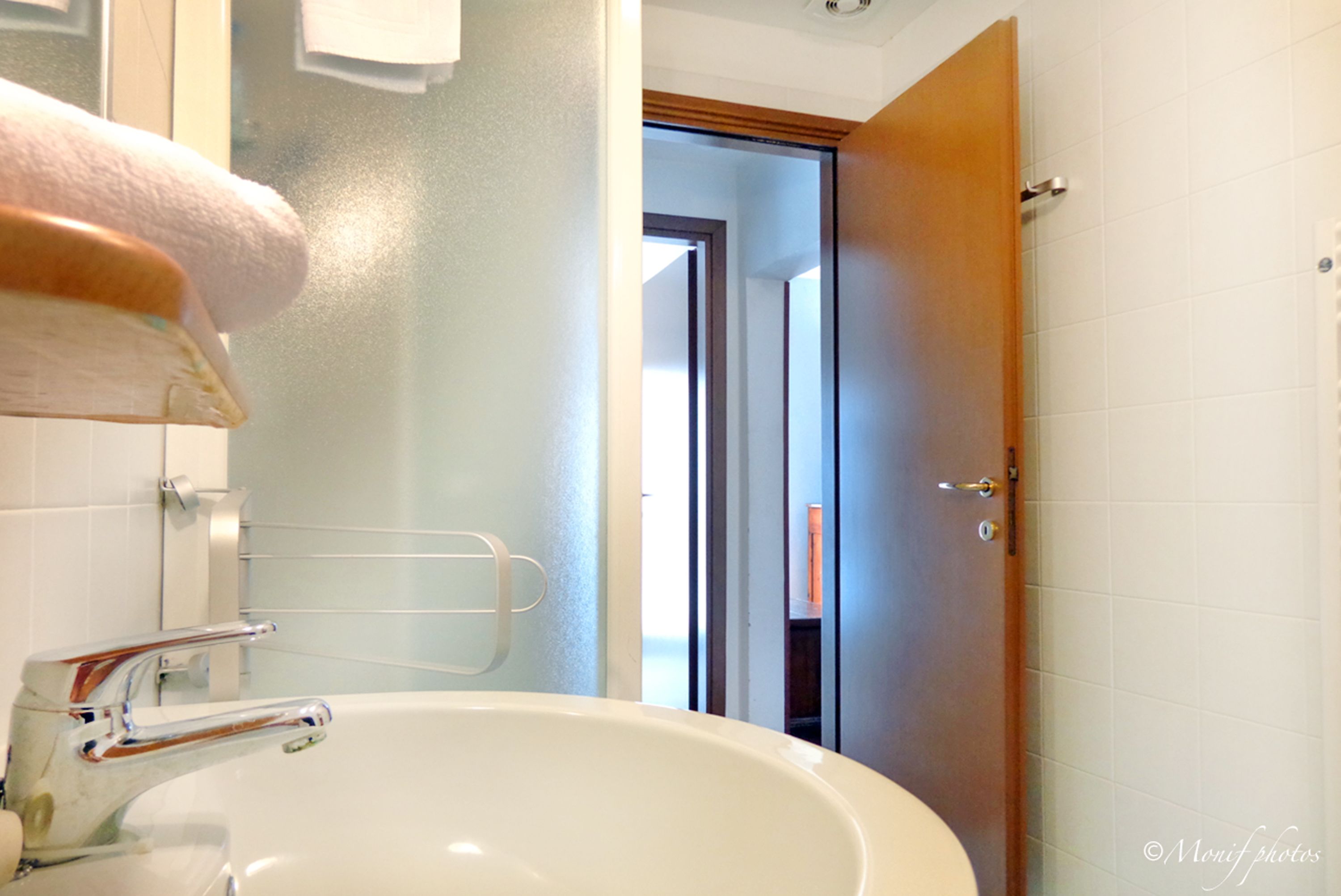 Une salle de bain avec un lavabo blanc, un robinet chromé et un porte-serviettes.