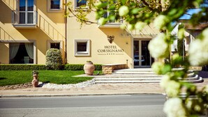A hotel entrance with a sign reading "Hotel Corsignano," a paved driveway, and a large terracotta pot. - Hotel Corsignano (Pienza)