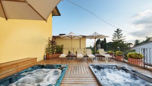 Une terrasse en bois avec deux bains à remous, des sièges d’extérieur et des parasols.