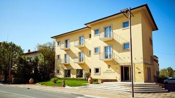 A multi-story hotel with balconies, a clear entrance, and a well-maintained lawn.