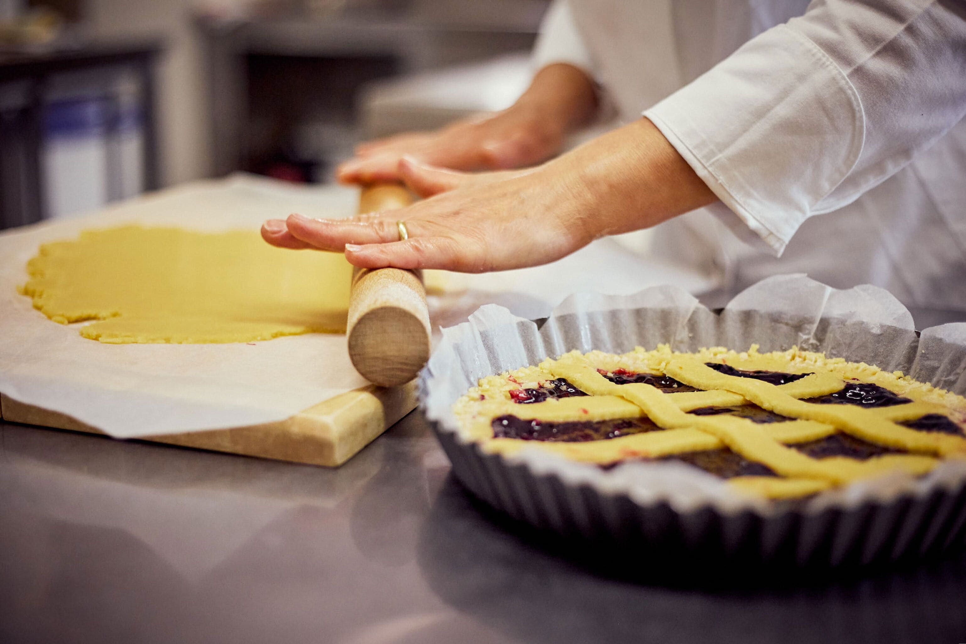 A person rolling dough on a kitchen counter.