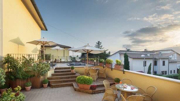 Une terrasse dotée de meubles en osier, de plantes en pot et de parasols.