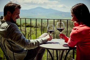 Dos personas sentadas en una mesa redonda al aire libre, con una vista panorámica de montañas al fondo.