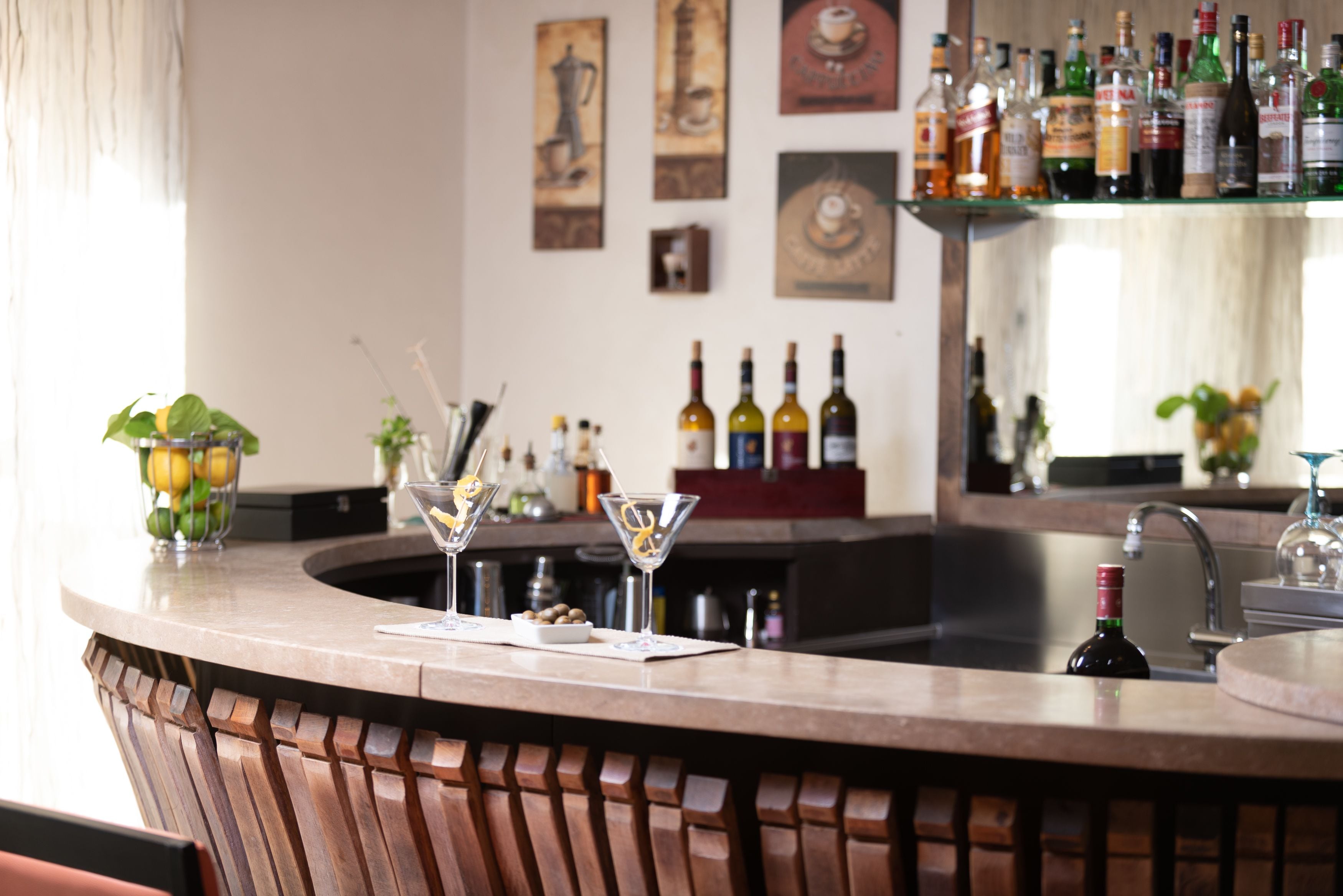 Eine Bar mit einer gebogenen Theke, einem Spülbecken und verschiedenen Flaschen und Gläsern.