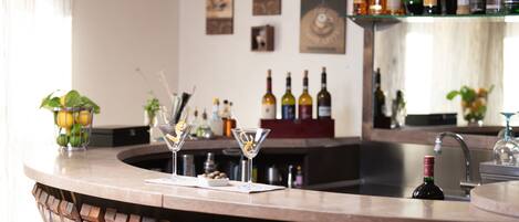 A bar area with a curved counter, a sink, and various bottles and glasses.