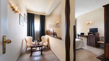 A hotel room with a dining area, a bed, a desk with a computer, and a television.