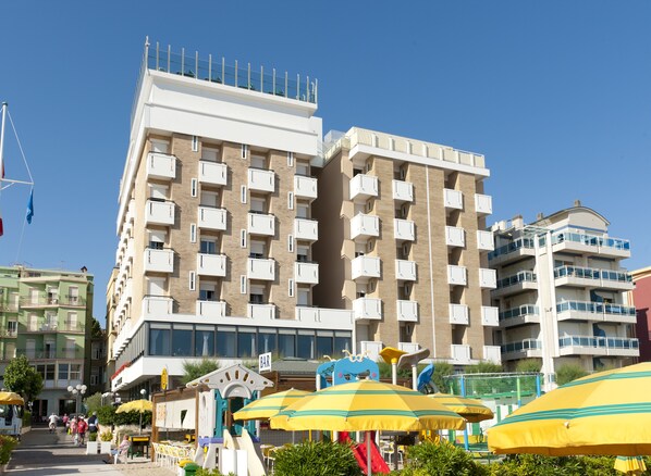 A multi-story hotel with balconies, a children's play area, and outdoor seating. - Hotel Napoleon (Gabicce Mare)