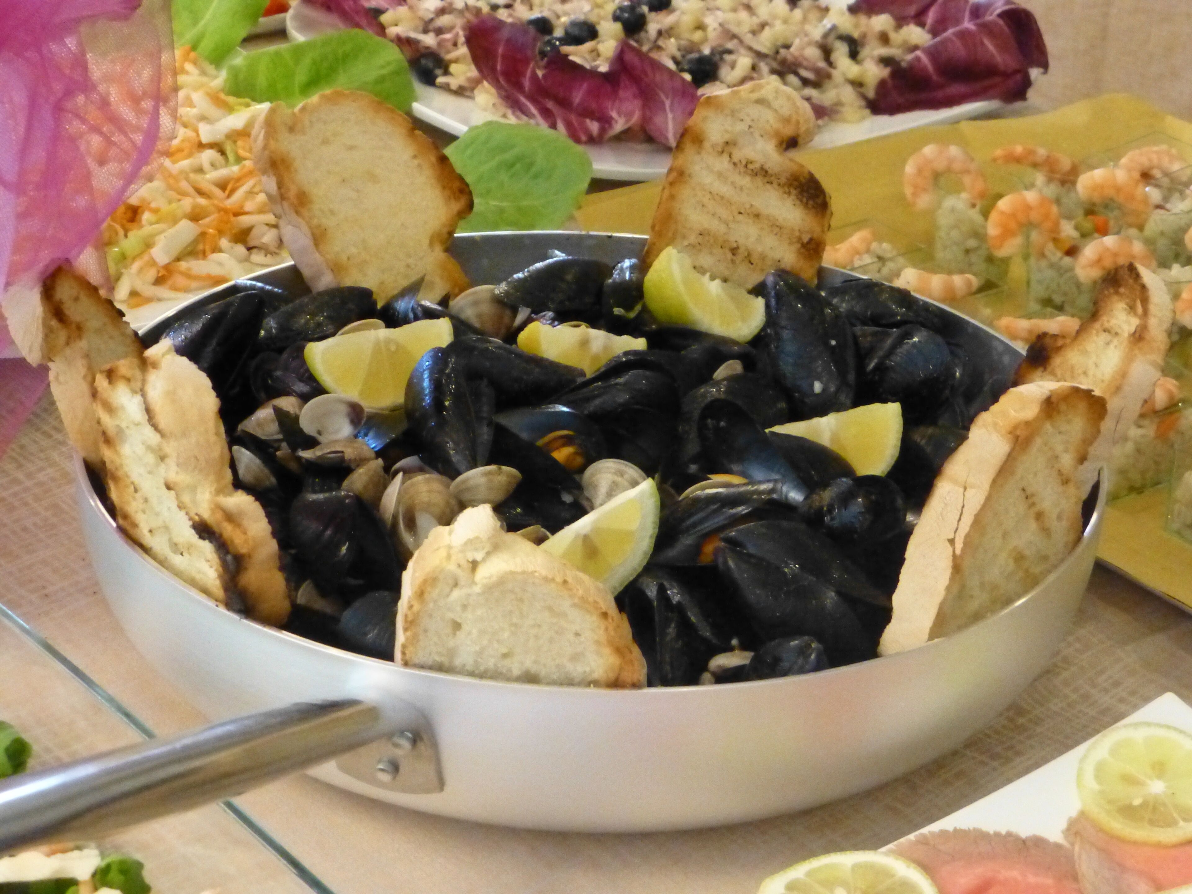 Ein Fischgericht mit Muscheln, Brot und Zitronenscheiben.