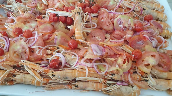Un plato de mariscos con camarones, tomates y cebollas.