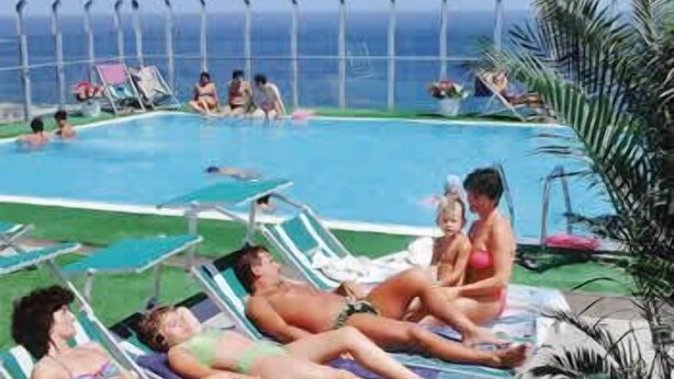 A pool area with lounge chairs and a view of the ocean. - Hotel Napoleon (Gabicce Mare)