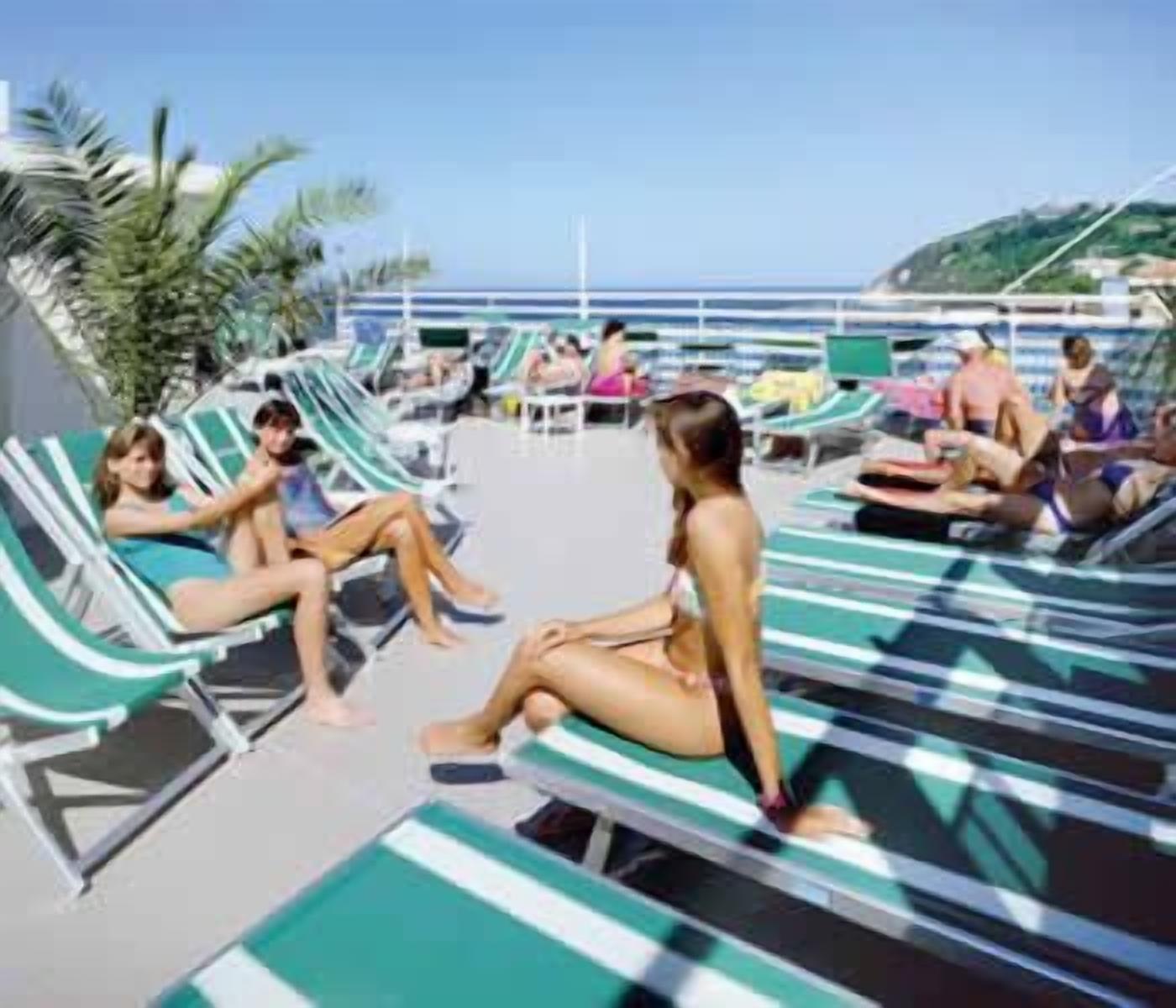 A poolside area with lounge chairs and a view of the ocean.