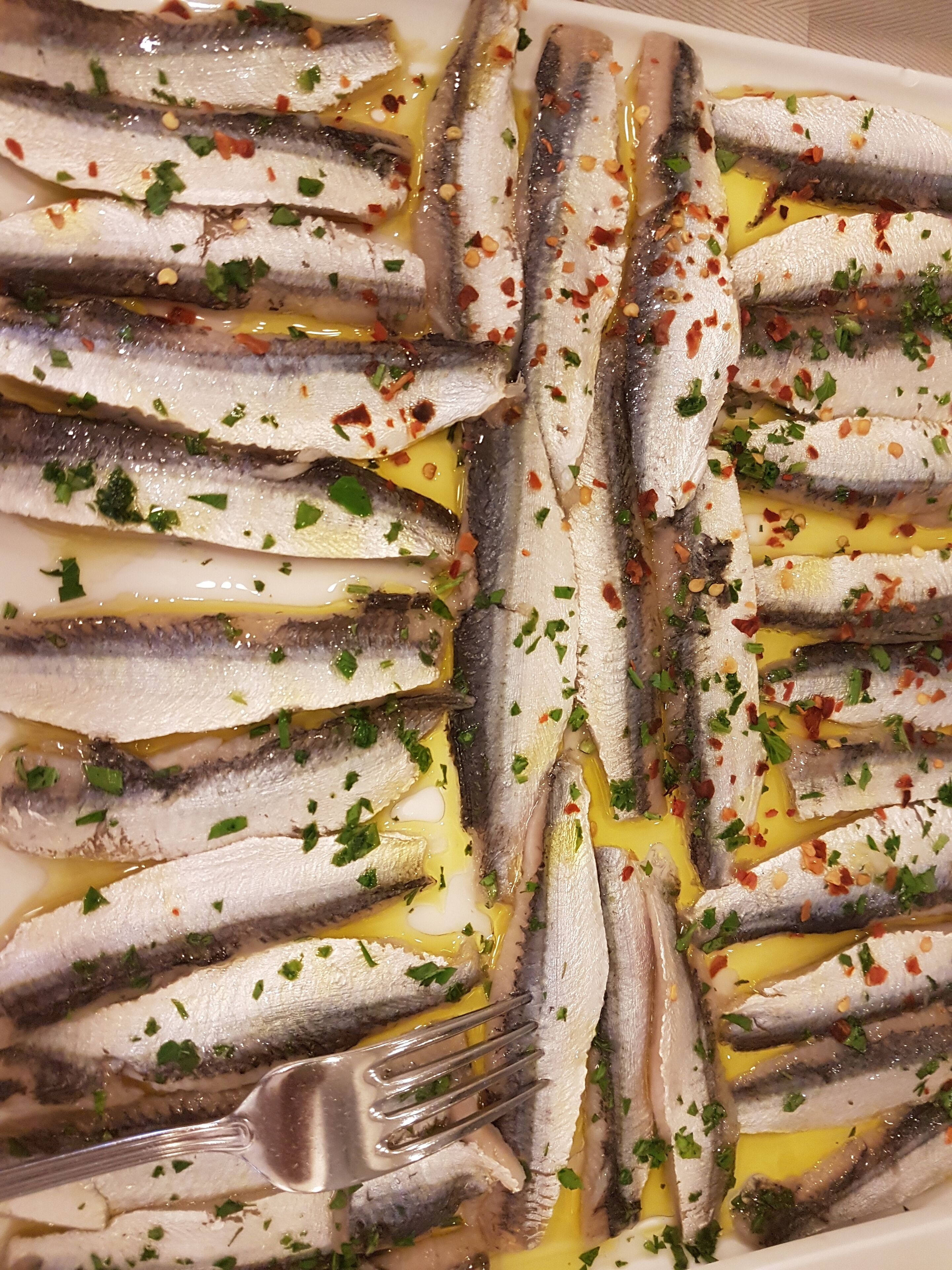 A plate of cooked sardines garnished with herbs and spices.
