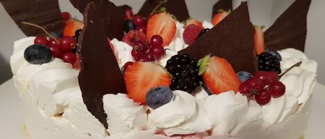 A dessert with whipped cream, strawberries, blueberries, blackberries, and chocolate pieces.