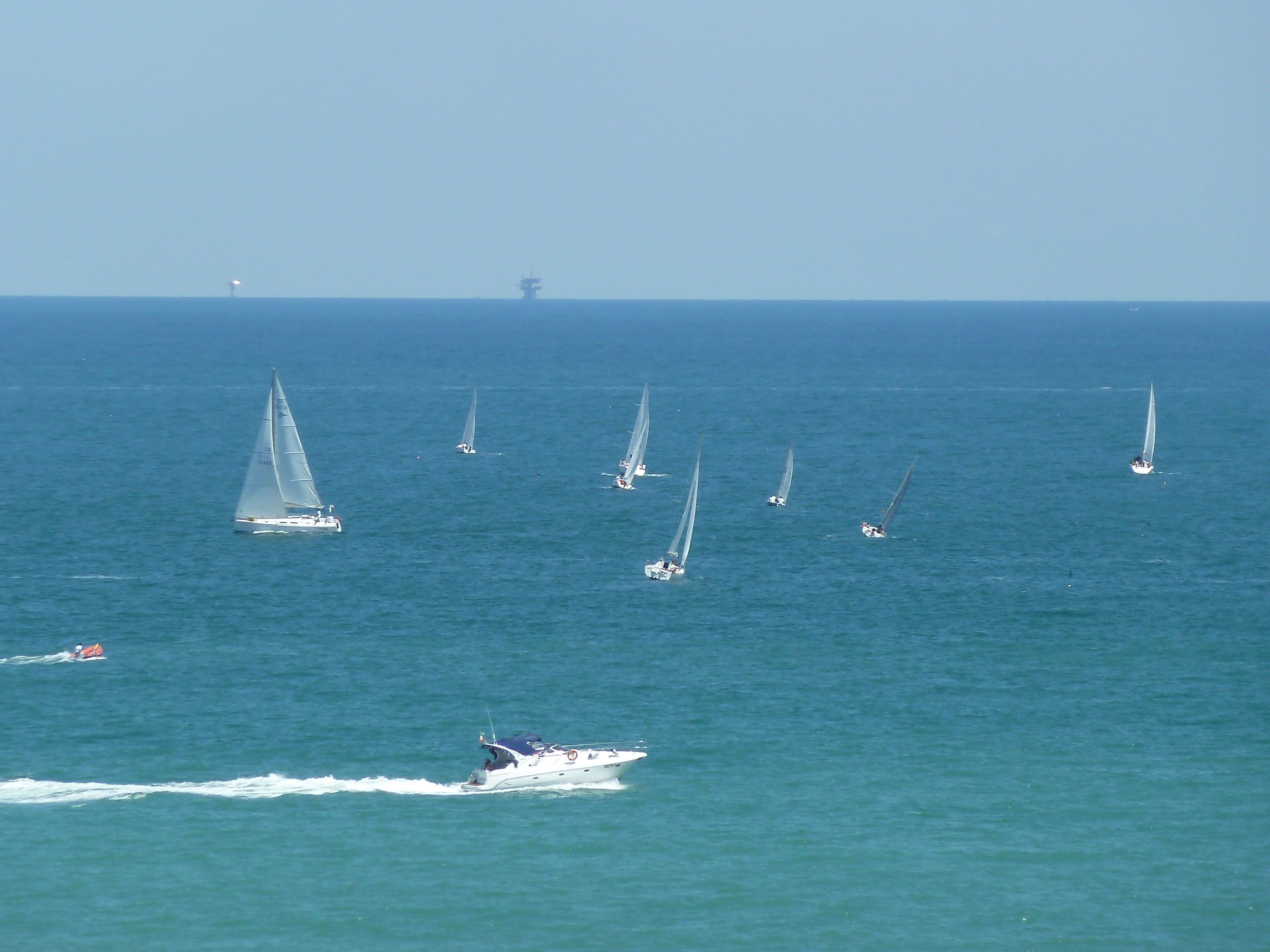 A marina with several sailboats and a speedboat.