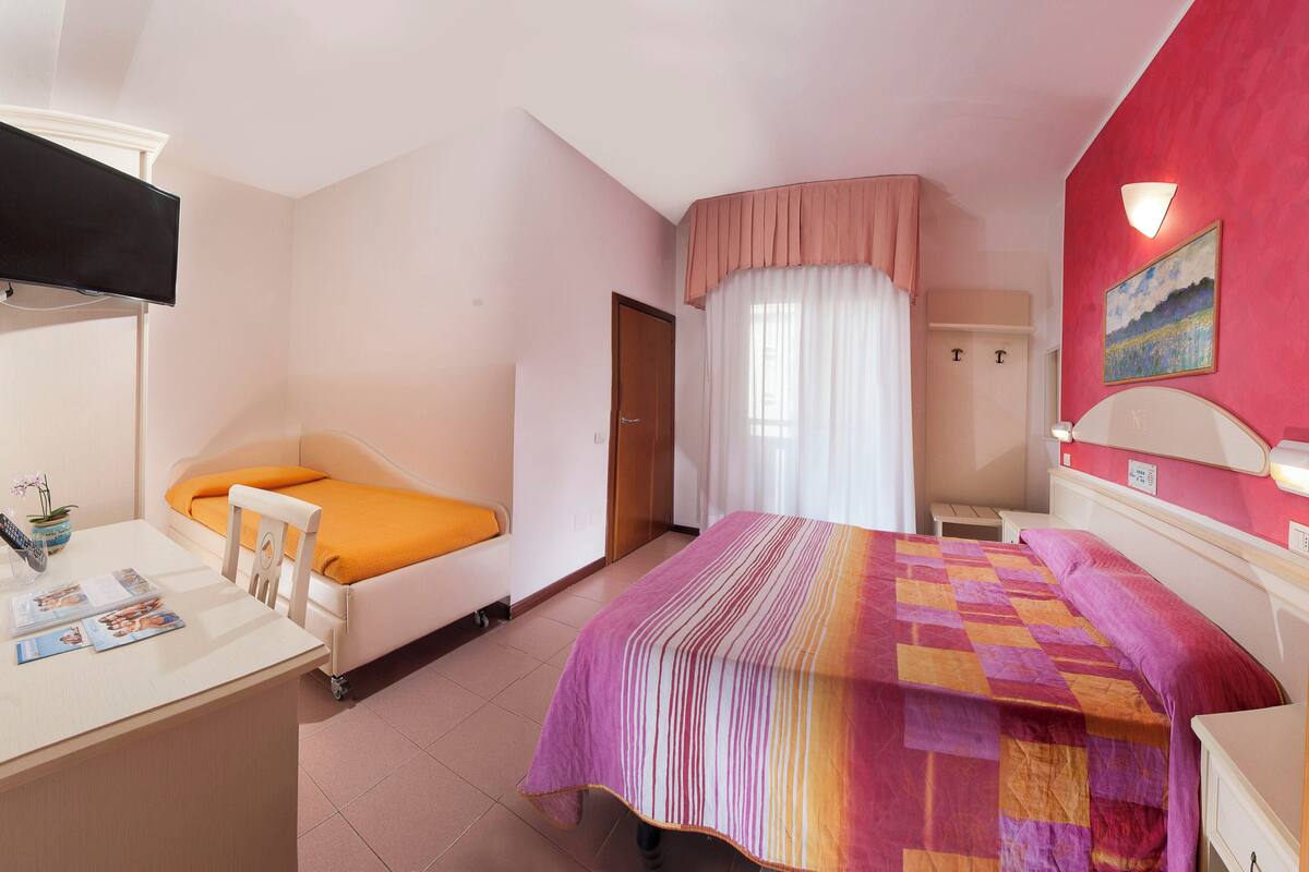 A bedroom with a bed, a desk, and a TV.