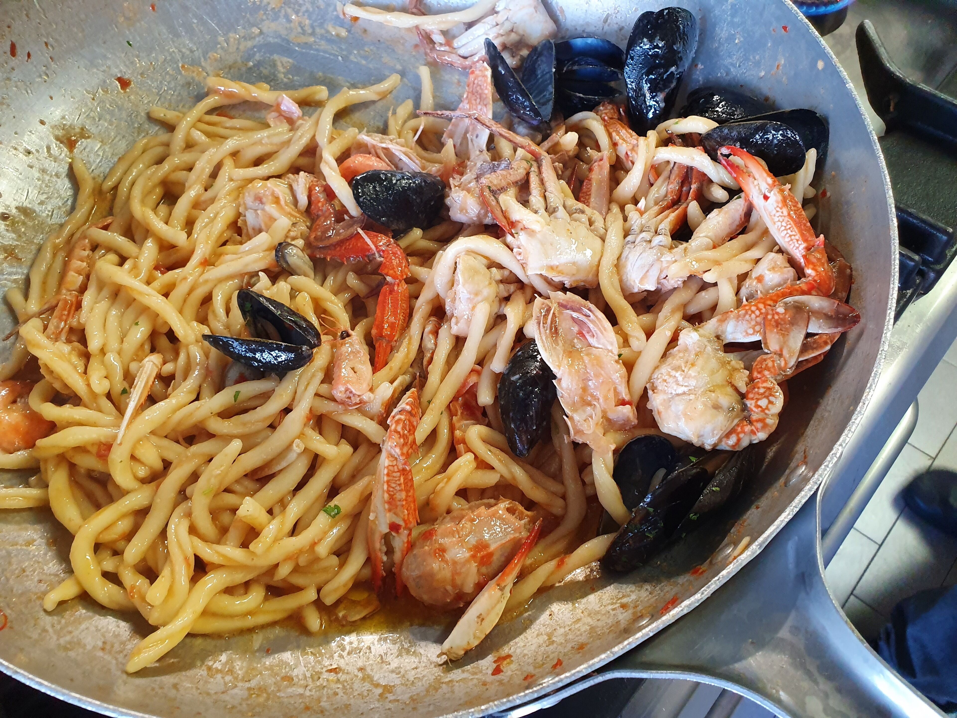 Una padella con pasta, gamberi e cozze.