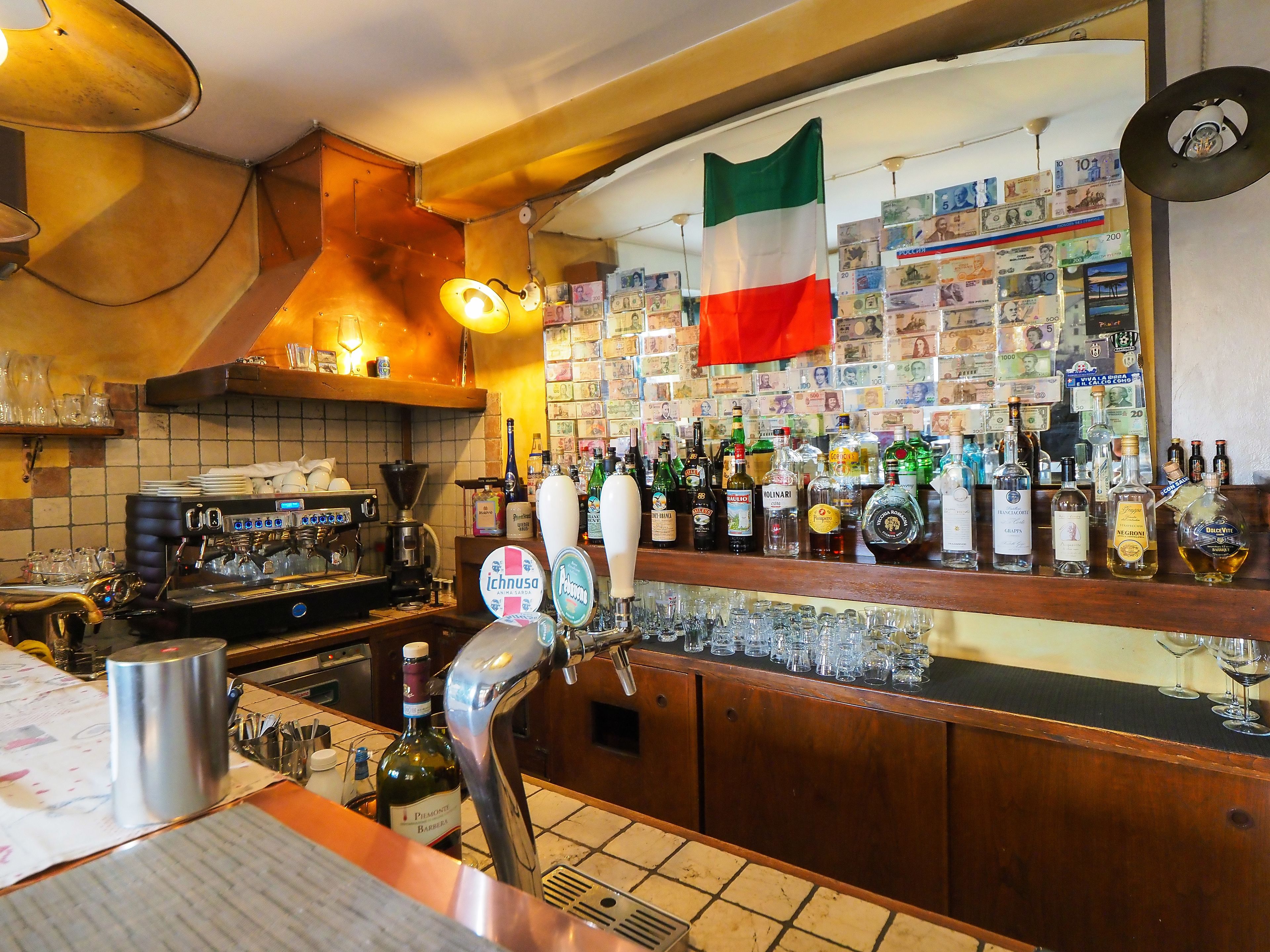 Egy bár, ahol van kávéfőző, különféle alkoholos italok és egy zászló.