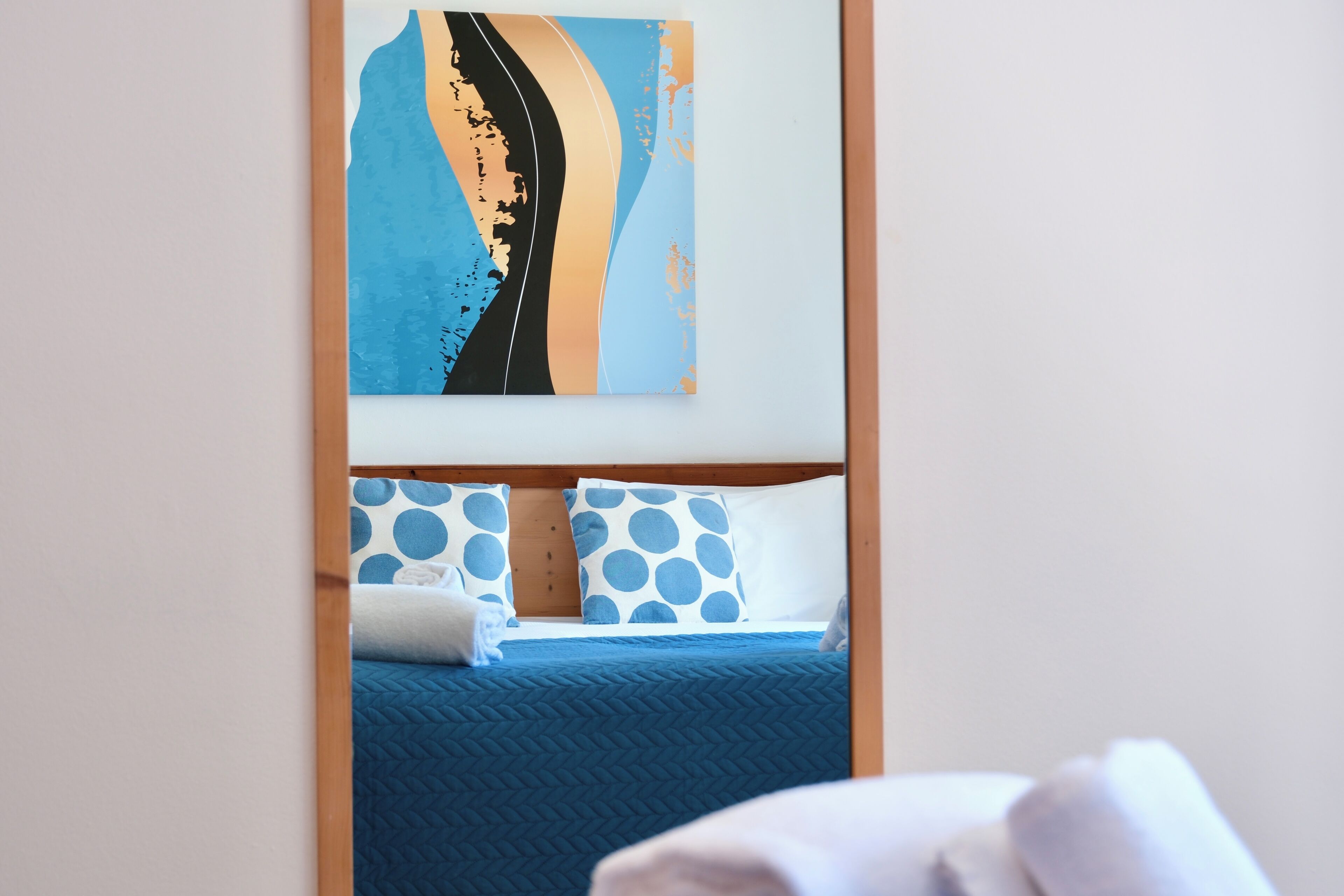 A hotel room with a bed, pillows, and a wall art piece.